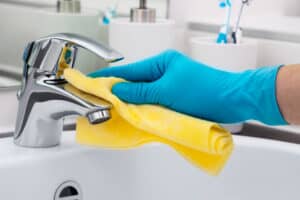 Person cleaning a sink faucet